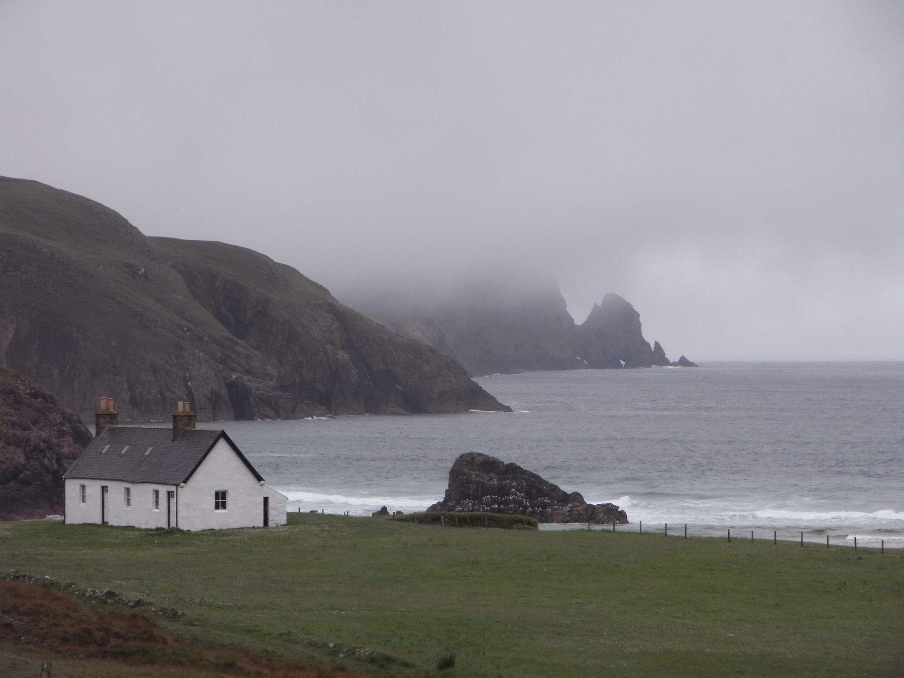 A remote Scottish cottage beside a misty coast