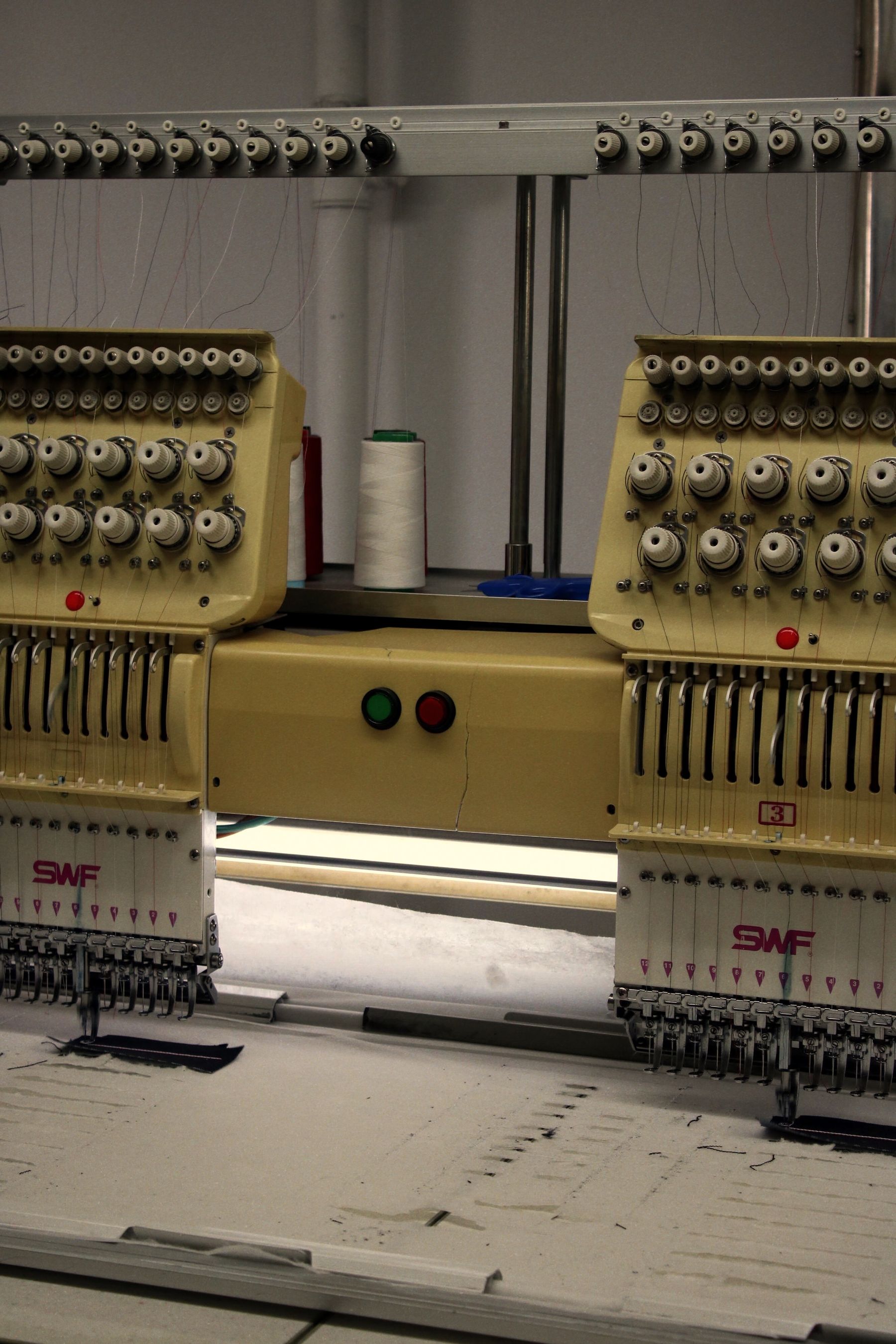 Threaded heads on an industrial embroidery machine in a textile workshop