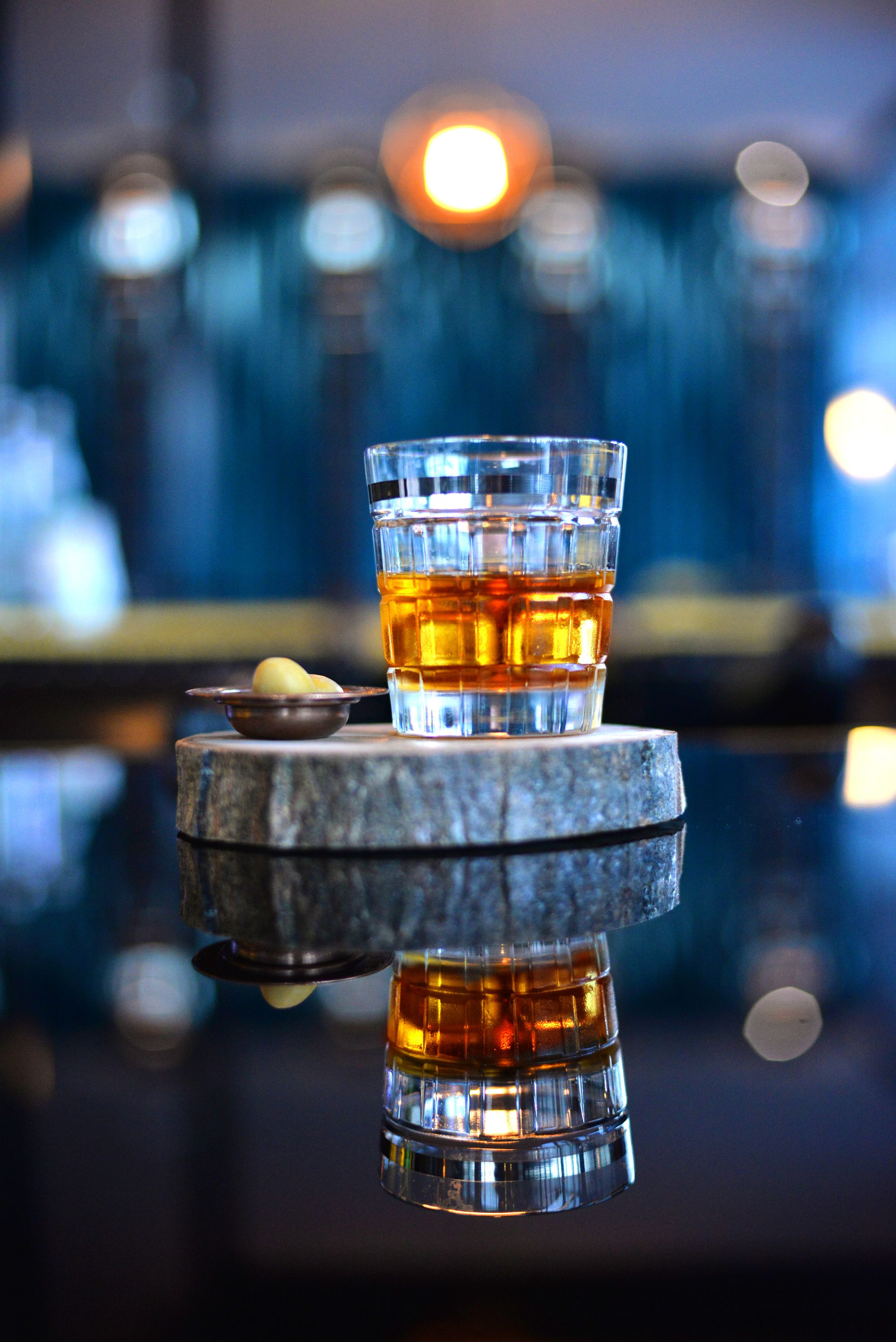 A cut-glass whisky tumbler reflected on a dark bar