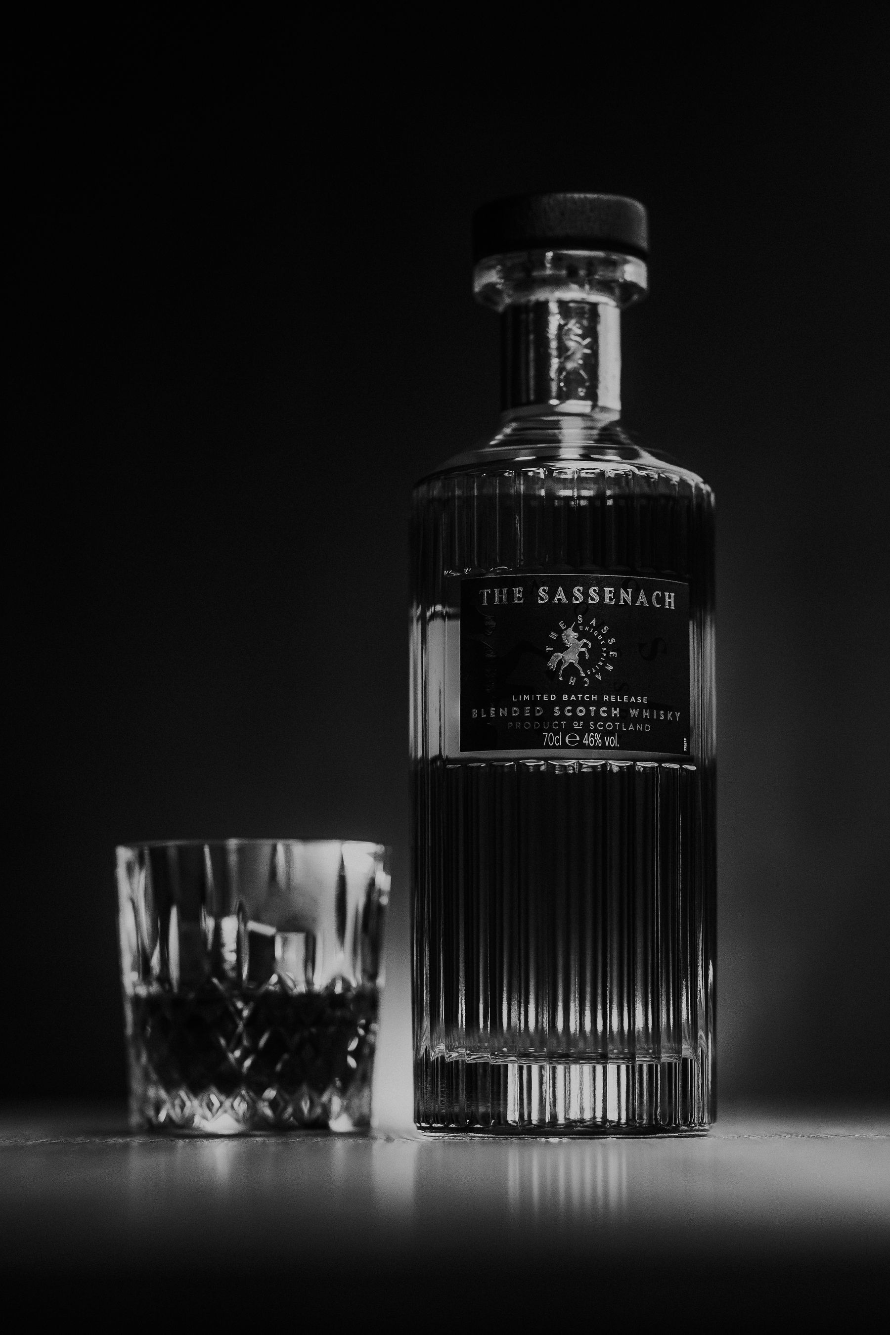 A Scotch whisky bottle and cut crystal glass in monochrome light