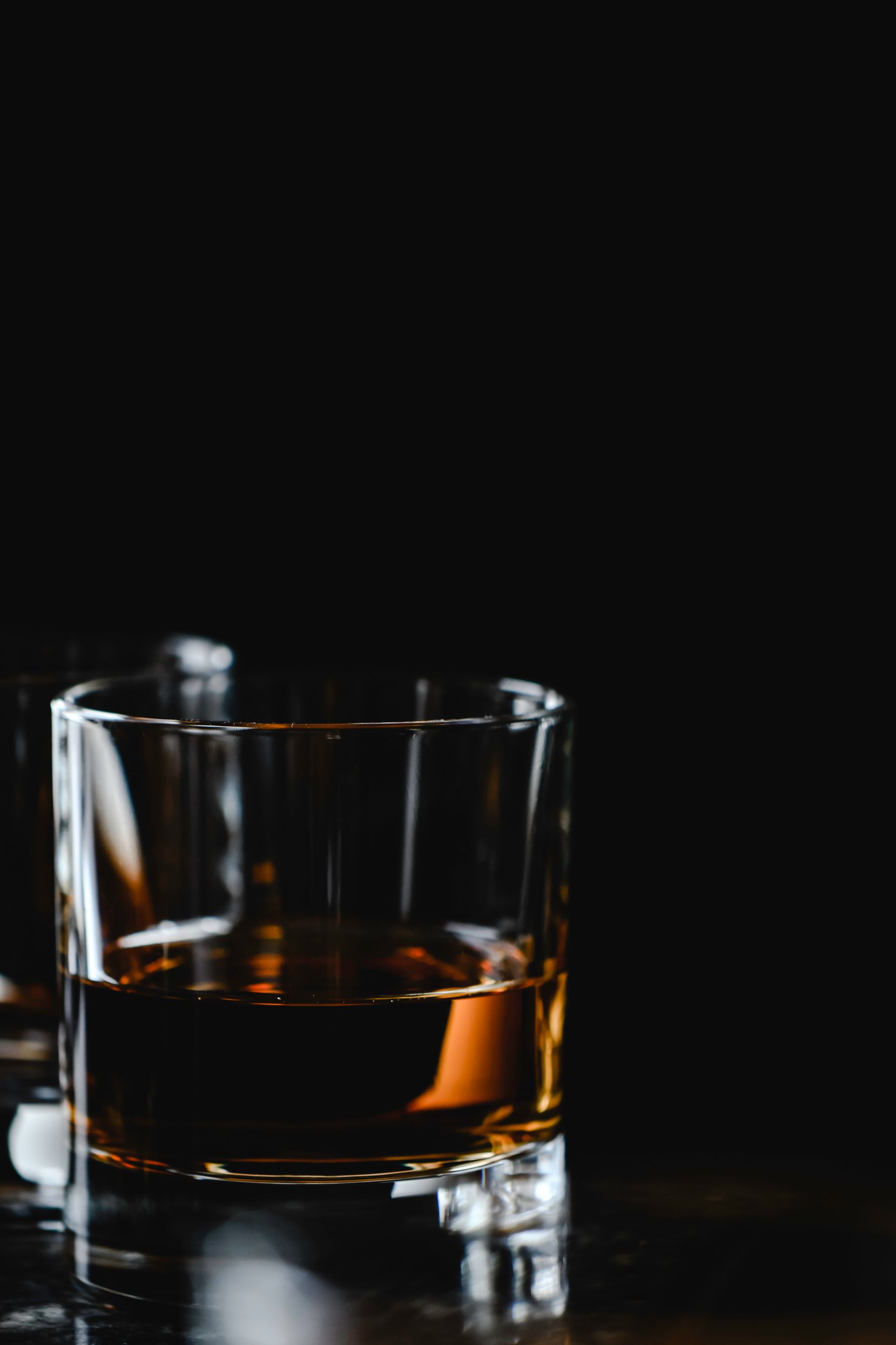 A close view of amber whisky in a glass against black