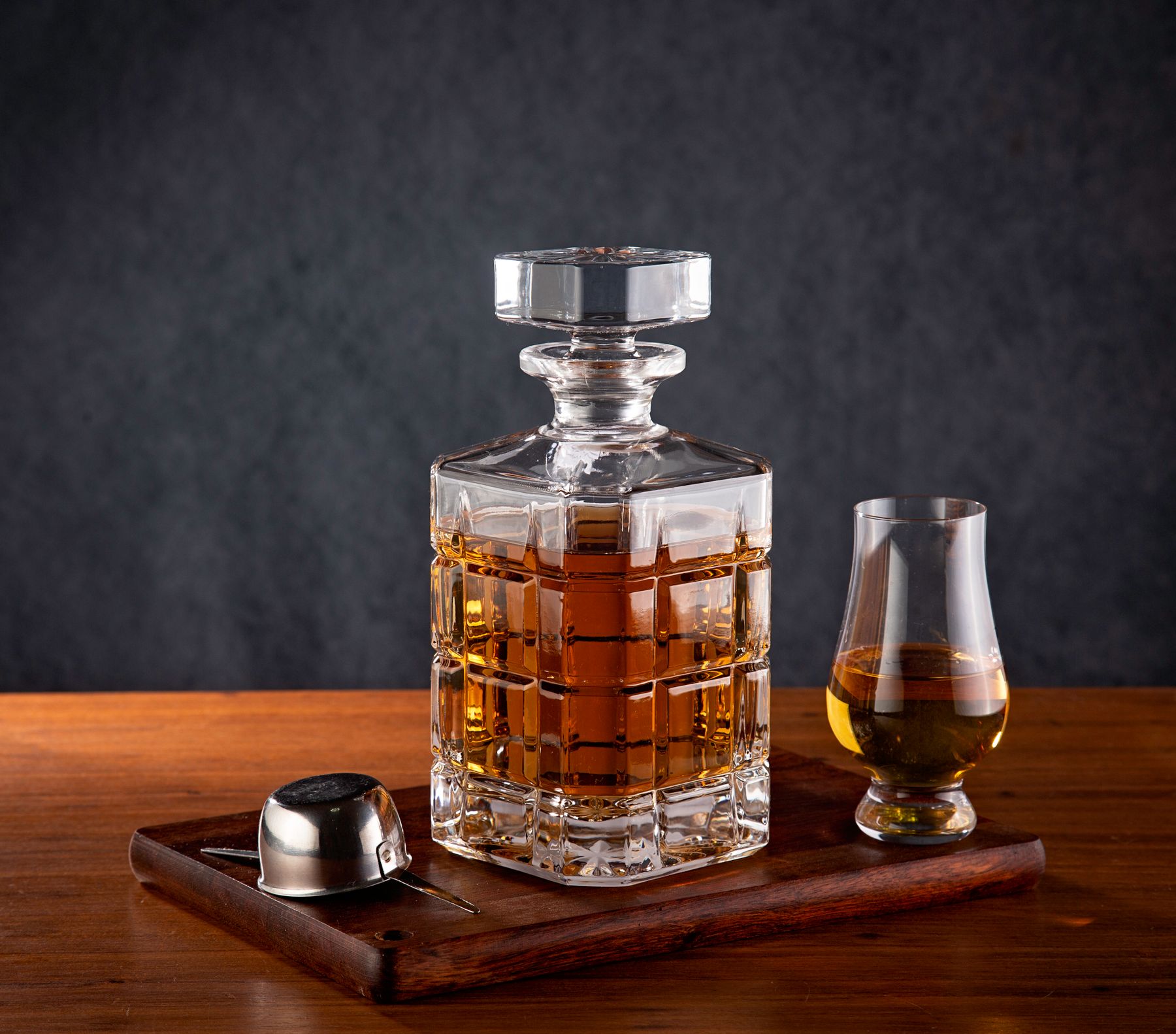 A whisky decanter and glass presented on a wooden tray
